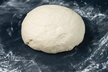 A piece of yeast dough on blue textured table. Process of making bakery. Adjarian Khachapuri Recipe – Georgian cheese bread.