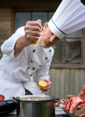 Chef prepares marinated meat  with a lemon for outdoor barbecue