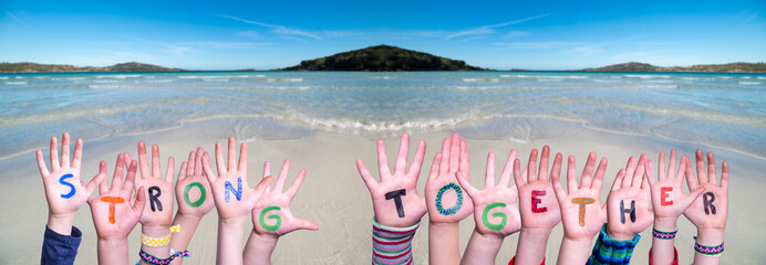 Children Hands Building Colorful Word Strong Together. Ocean And Beach As Background