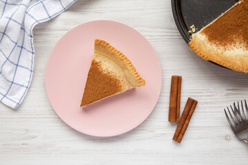Homemade Sugar Cream Pie on a pink plate on a white wooden surface, top view. Flat lay, overhead, from above.