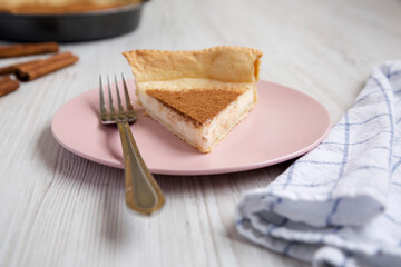 Fototapeta na wymiar Homemade Sugar Cream Pie on a pink plate on a white wooden table, side view.