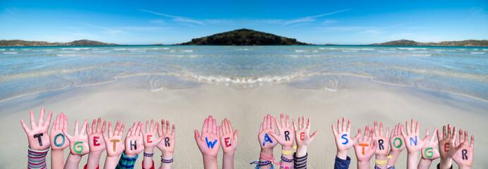 Children Hands Building Colorful Word Together We Are Stronger. Ocean And Beach As Background