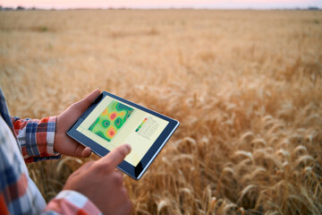 Precision farming. Farmer hands hold tablet using online data management software, differential...