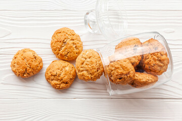 Homemade oatmeal cookies on white wooden table with milk on background