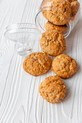 Homemade oatmeal cookies on white wooden table with milk on background