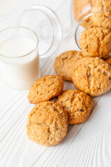 Homemade oatmeal cookies on white wooden table with milk on background