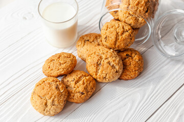Homemade oatmeal cookies on white wooden table with milk on background