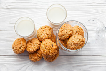 Homemade oatmeal cookies on white wooden table with milk on background
