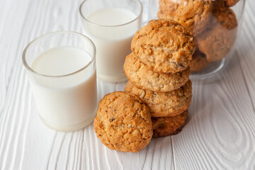 Homemade oatmeal cookies on white wooden table with milk on background
