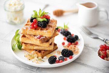 homemade waffles with berries, powdered sugar, drizzled with honey