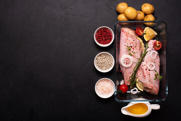raw fish perch in a glass baking sheet with spices and potatoes