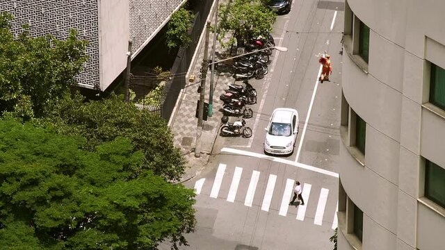 B-roll off a cross walk on big city. White car stoped in the traffic lights, some people passing by and an old woman crossing the street. Footage from the city of S&atilde;o Paulo in Brazil.