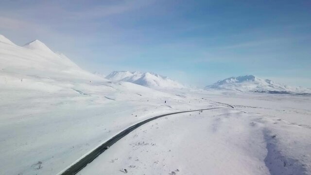 Spectacular white winter wonderland scene above Yukon Haines highway, route of old Dalton Trail, towards snow covered mountain ranges on colorful blue sunny sky day, Alaska, overhead aerial approach