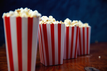 Popcorn in striped retro red and white cardboard box for cinema on wooden table