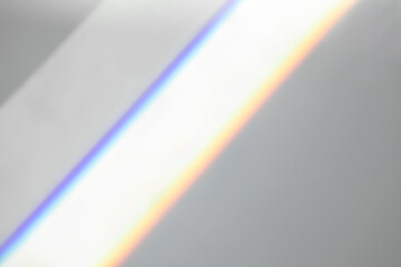 Overlay effect for photo and mockups. Organic drop diagonal shadow and ray of light with rainbow from window on a white wall.
