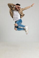sexy young casual guy in jacket wearing sunglasses and jumping