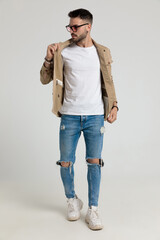 cool young fashion guy looking to side and fixing jacket
