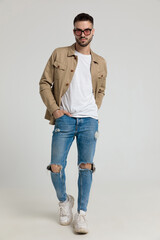 sexy young man in jacket holding hands in pockets and walking