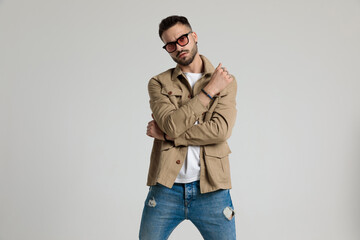 serious young man in jacket holding elbows in a fashion pose