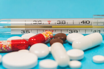 pills and thermometer on a blue background, the concept of a flu epidemic