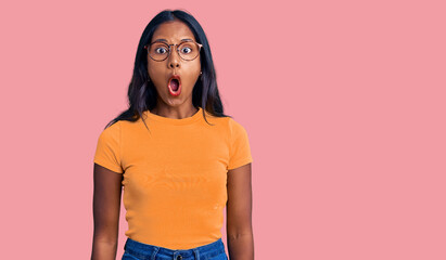 Young indian girl wearing casual clothes and glasses afraid and shocked with surprise expression,...