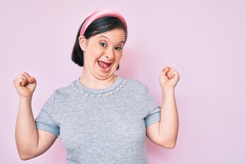 Brunette woman with down syndrome wearing casual clothes screaming proud, celebrating victory and success very excited with raised arms