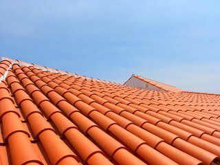 Fototapeta Red tile roof under blue sky. The photo is divided in half. One part is a roof made of clay tiles and the other is a pure blue sky. obraz