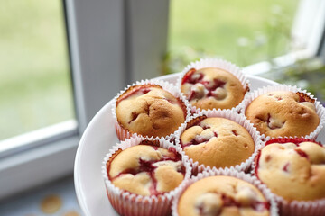 Plate with strawberry muffins over kitchen window background