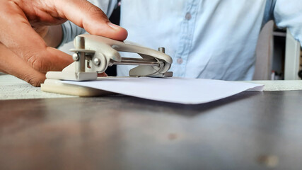 a businessman making holes in a paper using small tool