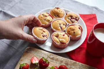 Strawberry muffin with fresh strawberries in hand, sweet summer dessert