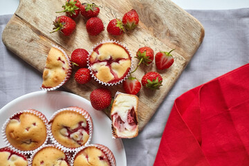Homemade summer pastry flat lay - strawberry muffins on wooden cutting board