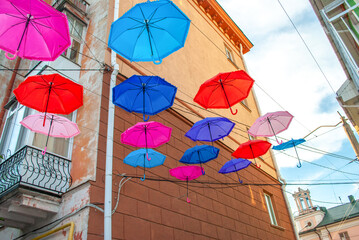 Lot of flying colorful parasol hanging in summer village