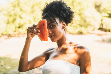 Attractive African descent woman with a slice of watermelon in the countryside. Healthy lifestyle...
