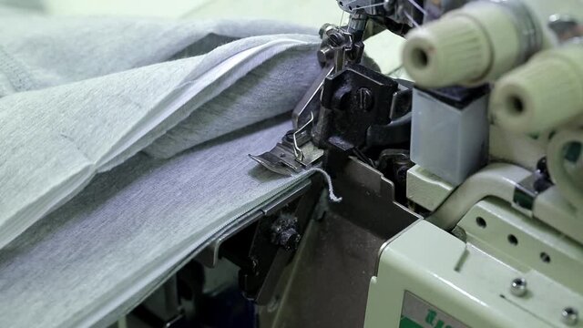 Close-up of a woman's hands handling fabric on an overlock machine.Textile industry.