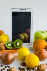 Digital tablet with white,blank screen stand near fresh fruits and nuts.Conceptual image of online shopping.
