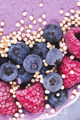 Healthy yogurt and fruit smoothie bowl decorated with raspberry, blueberry and puffed quinoa grain