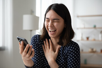 Overjoyed Asian millennial girl laugh at funny joke video online on cellphone gadget, excited happy Vietnamese young woman have fun using smartphone, text message, easy usage, entertainment concept