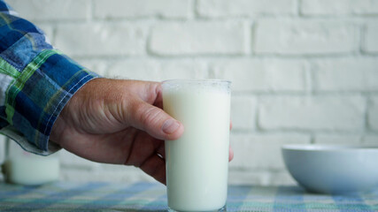 One Person takes and drinks a Glass with Fresh Milk at Breakfast a Healthy, Tasty and Natural Drink Full with Protein and Vitamins