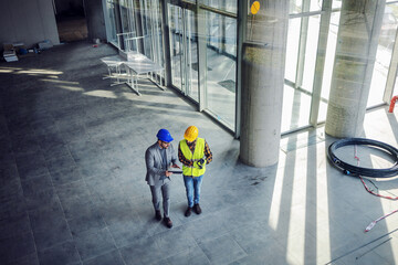 Top view of contractor and architect walking around building in construction process and talking...