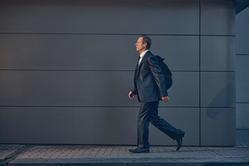 Handsome man with backpack walking on the street