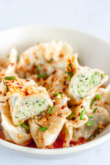 Chicken Dumplings / Wonton in Spicy Sichuan Sauce in a Bowl Close Up Vertical Photo