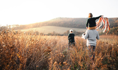 Rear view of family with small daughter on a walk in autumn nature.