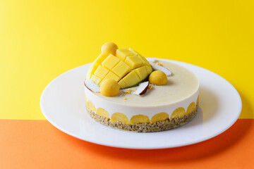 Cashew cake with mango and coconut on a yellow-orange background. Sugar, lactose, gluten free.
