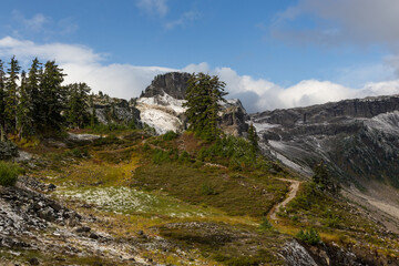 Fototapeta na wymiar Hiking trail in mountains area. North Cascades National park, Washington, USA. Fresh snow clouded nearby hills