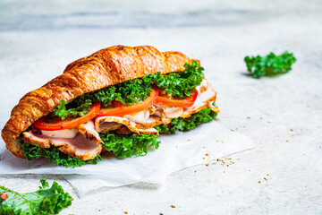 Croissant sandwich with meat, vegetables and green kale, white background. Breakfast food concept.