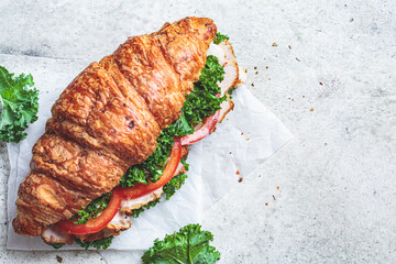 Croissant sandwich with meat, vegetables and green kale, white background. Breakfast food concept.