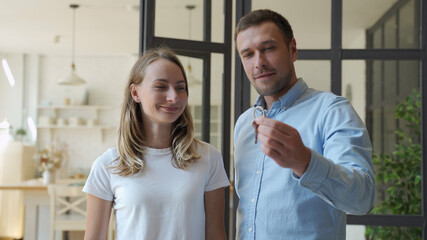 Happy couple receiving apartment key from real estate agent. Happy couple smiling and getting keys from new real estate from agent.