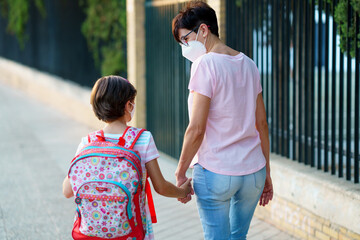 Nine years old girl with bag walking with her mother hand in hand.