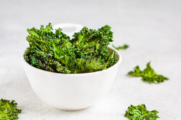 Green kale chips with salt in white bowl. Healthy vegan food concept.