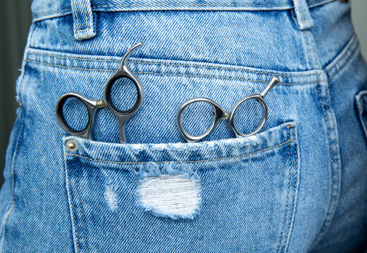 professional hairdressing scissors lie in the back pocket of jeans .